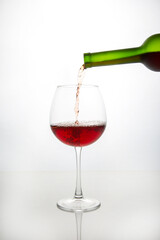 red wine from a bottle is poured into a glass on a light background. alcoholism and addiction. drinks for the holiday