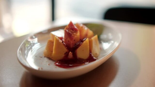 Plate of chopped mango with Mexican chamoy sauce and blurry background