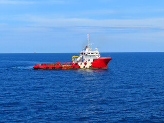 Fototapeta premium Supply boat transfer the cargo for supporting oil and gas industry and moving cargo from the boat to the platform. Boat is waiting transfer cargo and crews to platform. 
