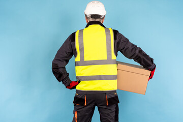 warehouse worker with his back to camera. Man in a yellow vest and helmet. warehouse worker with a...