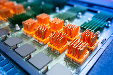 Computer board with orange heatsinks. PCB heat sinks are equipped with heat sinks. Individual heatsinks on computer board. Multicolored PCB close up. Microprocessor-based heat dissipation devices - obrazy, fototapety, plakaty