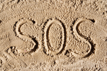 SOS - word drawn on the sand beach. Inscription on sand from shells - sos, camping, hiking danger,...