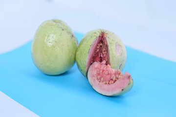 Fresh sliced guava and leaves or Psidium guava, isolated on blue. Selective Focus.