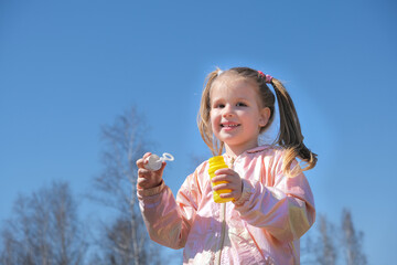 Little girl  blowing soap bubbles . Active child walking in the park. Family lifestyle, outdoors activities, summer holidays with kids.