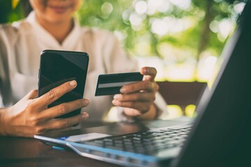 A woman uses her phone with credit card in hand  Online trading on a global network via the...