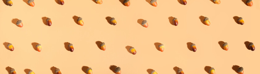 Autumn pattern of oak brown nut acorns on peach orange pastel background.Fall background concept