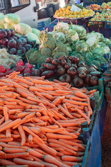 A vibrant farmers' market stall displaying fresh carrots, beets, and cabbages. The colorful array of vegetables highlights the freshness and variety available at local markets.