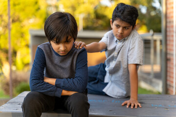 Friends caring concept. Resolving conflict with angry child. Two young boys together. Hand on shoulder. Kids communication concept.