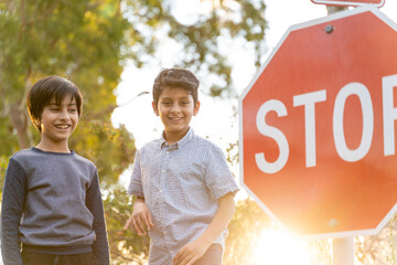Friendship concept with diverse children. Two young kids laughing next to stop sign. Golden hour scene of happy kids having fun.