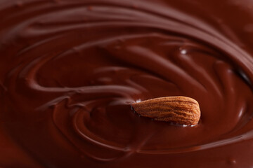 Almonds are drowning in melted chocolate. Chocolate background. Selective focus

