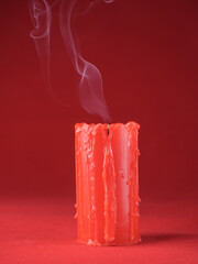 An extinguished red candle with smoke with smudges on a red background. Copy space.