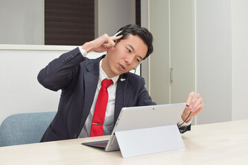 A young Asian man wearing a headset thinks about how to deal with her customer during telework at home