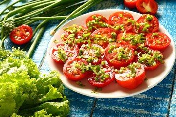 Plate of delicious homemade organic tomato salad. with fresh herbs and greens.
