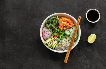 Keto diet poke bowl with salmon, avocado, and edamame beans. over dark background. top view, copy...