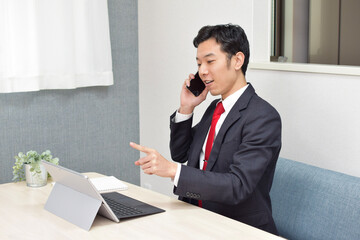 A young Asian man gets convinced while talking on his phone during telework at home