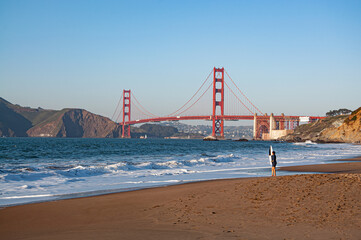 Golden Gate Bridge with beach and ocean waves on sunny day