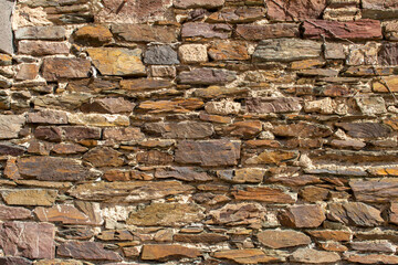 Close up full frame texture background of a medieval stone wall in colors of brown and beige