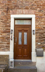 Close up view of a brown wooden European entryway door  on a medieval stone and brick wall building surface