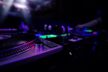 Fototapeta na wymiar Dj equipment at nightclub, mixer and turntable with record, colored image with copyspace