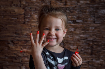 Children's manicure with red nails for Halloween. Halloween concept. A girl in a skeleton costume painted her nails for the holiday.