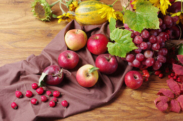 Apples, grapes and drapery on a wooden table. 