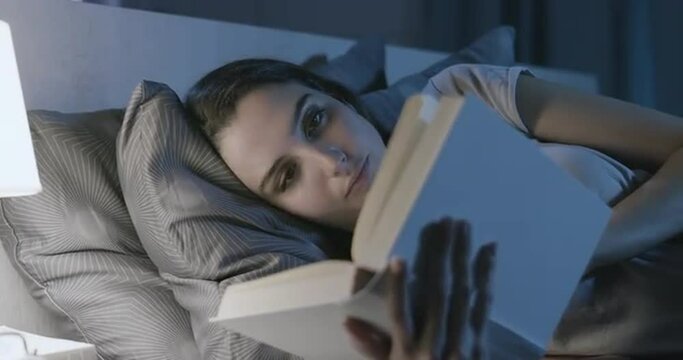 Woman relaxing in bed and reading a book