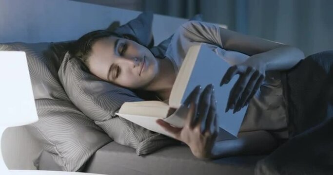 Woman relaxing in bed and reading a book
