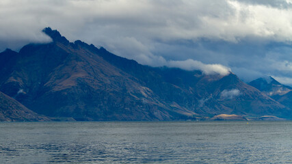 dark, misty mountain with low rolling clouds and lake