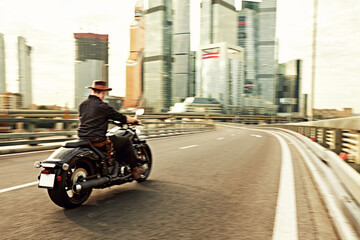 young man riding big bike ,motorcycle on city road against urban and town building scene. Motion blur
