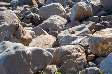 Large stones on the seashore are chipped from a rock whose corners were turned by water the foreground is blurry
