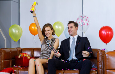 Caucasian businessman in business suit sitting on leather sofa with present gift box and balloons...