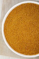 Organic Brown Sugar in a White Bowl, top view. Flat lay, overhead, from above. Close-up.