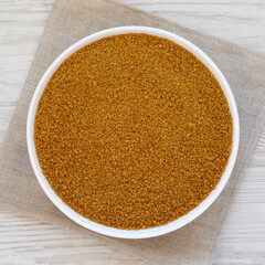 Organic Brown Sugar in a White Bowl on a white wooden surface, top view. Flat lay, overhead, from...