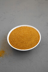 Organic Brown Sugar in a White Bowl on a gray background, side view.