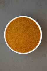 Organic Brown Sugar in a White Bowl on a gray background, top view. Flat lay, overhead, from above.