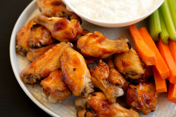 Homemade Chicken Wings with Blue Cheese Dip on a black background, side view.