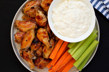 Homemade Chicken Wings with Blue Cheese Dip on a black background, top view. Flat lay, overhead,...