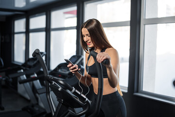 Attractive young sports woman is working out in gym. Doing cardio training on treadmill. Running on treadmill. High quality photo