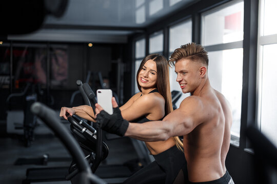 Athletic guy and a girl take a selfie in the gym. Sports concept, fat burning and healthy lifestyle. High quality photo