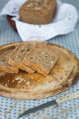Slices of homemade rye bread with seeds, sesame seed, flaxseed on round wooden plate