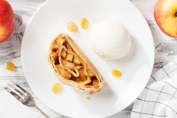 Traditional homemade apple strudel with caramelized apples and raisins , served with ice cream ball. top view	