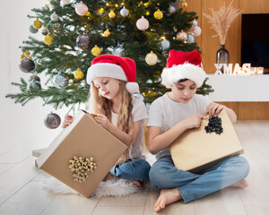 Obraz na płótnie Canvas Children - a boy and a girl are playing near the Christmas tree.
