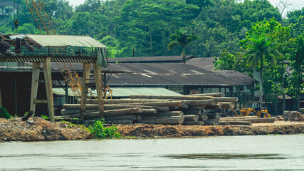 Fototapeta na wymiar Timber loaded into big barge then drag by a tugboat cruising Mahakam River, Borneo, Indonesia