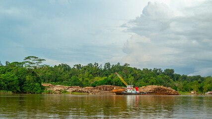 Fototapeta na wymiar Timber loaded into big barge then drag by a tugboat cruising Mahakam River, Borneo, Indonesia
