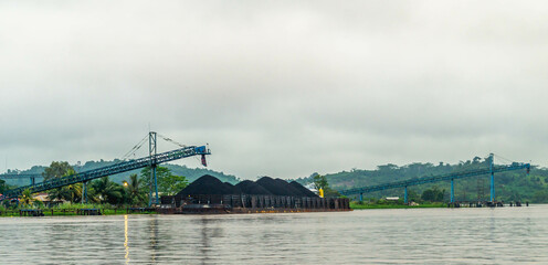 Fototapeta na wymiar Barge of coal loaded by conveyor, Mahakam River, Outback of Borneo, Indonesia
