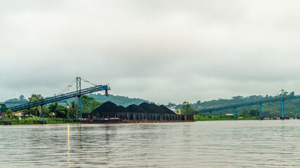 Obraz premium Barge of coal loaded by conveyor, Mahakam River, Outback of Borneo, Indonesia