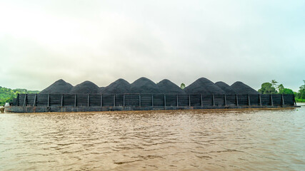 Barge full of black coal cruising on Mahakam River, Borneo, Indonesia. Mining and energy 