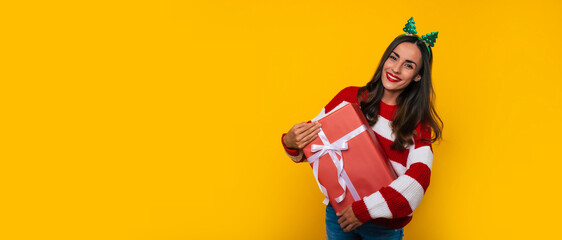 Wide banner photo of beautiful excited smiling woman with Christmas gift box in hands is having fun...