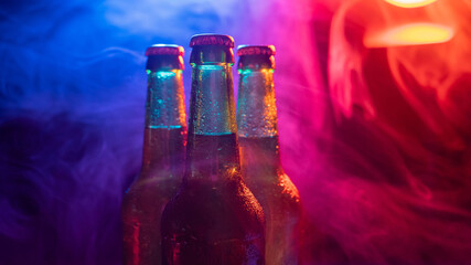 Three bottles of beer in a blue-pink mist.