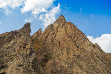 Pointed brown and yellow mountains with very sharp descents and expressive texture against the background of deep blue sky
